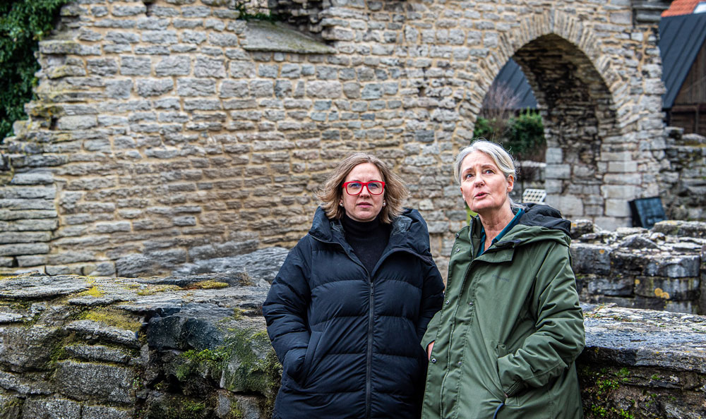 two women standing in front of a stone wall